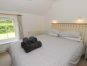 A bedroom with a bed, a window, and a radiator. - Cynefin (Newport)
