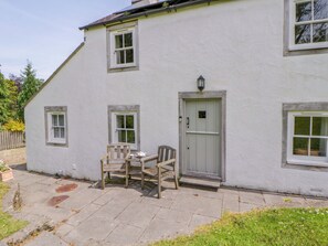A white building with a door, windows, and a small table with chairs. - Cynefin (Newport)