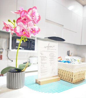 A kitchen with a welcome sign, a potted orchid, and a woven basket.