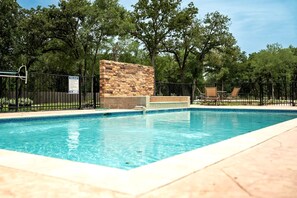Una piscina rectangular con una pared de piedra y una valla de metal negro.