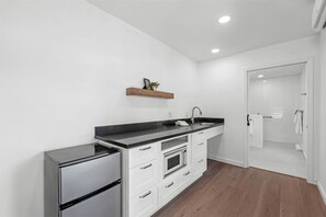 Una cocina moderna con horno empotrado, refrigerador, pileta y un estante de madera sobre la encimera.