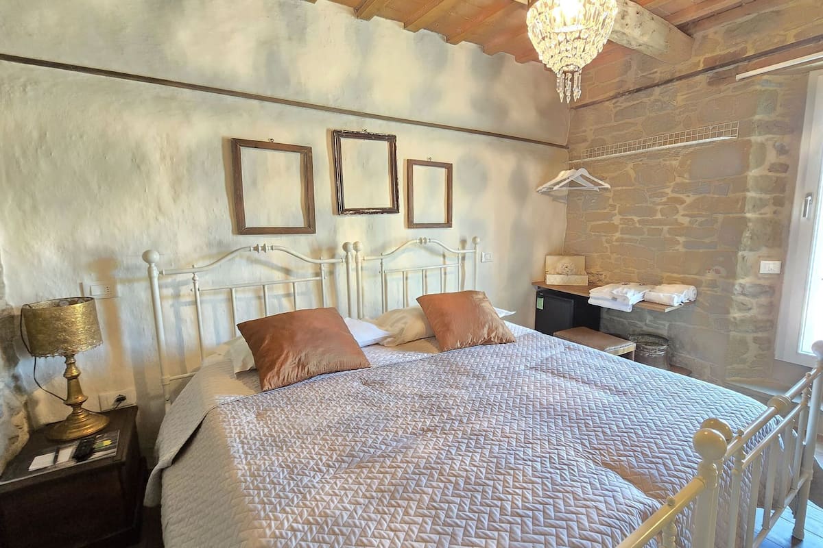 Camera da letto con un letto, un comodino, una lampada, un lampadario e una finestra con tende.