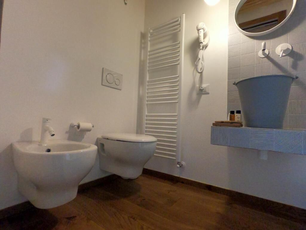 Une salle de bain équipée d’un bidet, de toilettes, d’un porte-serviettes et d’un miroir.