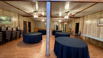 A conference room with round tables, chairs, and wooden walls.