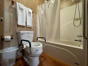 Une salle de bain avec des toilettes, une baignoire et un rideau de douche.