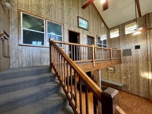 Un intérieur en bois avec un escalier, un banc et un ventilateur de plafond.