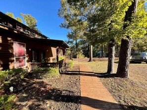 Une cabane en bois avec une véranda, un sentier et des arbres tout autour.