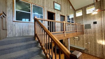 Un intérieur en bois avec un escalier, un banc et un ventilateur de plafond.