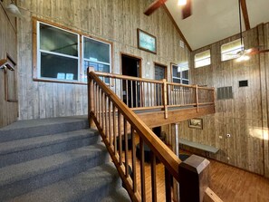 Un intérieur en bois avec un escalier, un banc et un ventilateur de plafond.