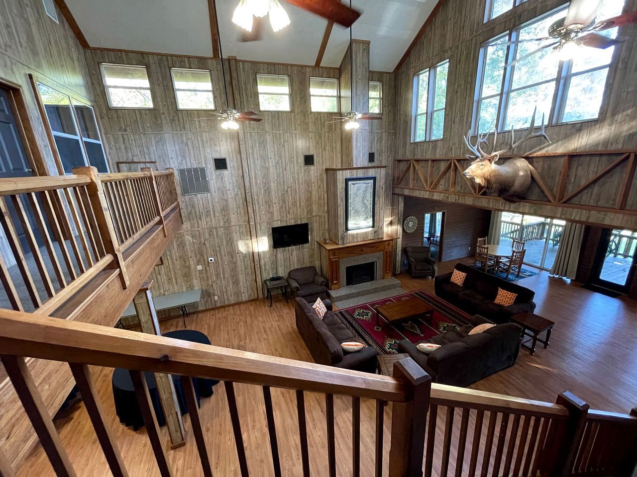 A spacious living area with a fireplace, multiple seating options, and a large window with a deer head decoration.