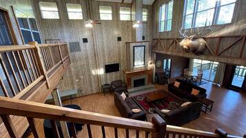 A spacious living area with a fireplace, multiple seating options, and a large window with a deer head decoration.