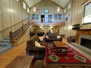 Un intérieur spacieux avec un escalier en bois, plusieurs coins salon et une cheminée.