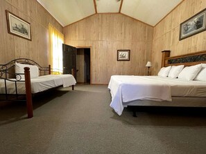 Ein Zimmer mit zwei Einzelbetten, Holzboden und einer Tür zu einem weiteren Raum.