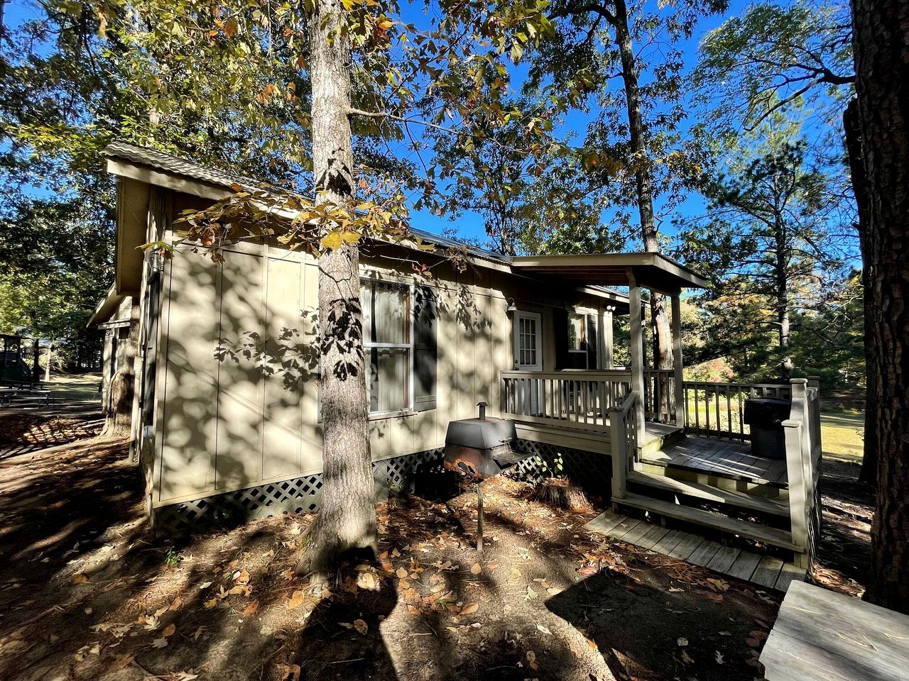 Ein kleines Blockhaus mit Veranda, Schornstein und einem eingezäunten Garten.