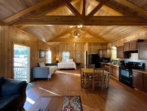 L’intérieur d’une cabine est aménagé avec du bois, il comprend un lit, une table à manger avec des chaises, un coin cuisine et un balcon.