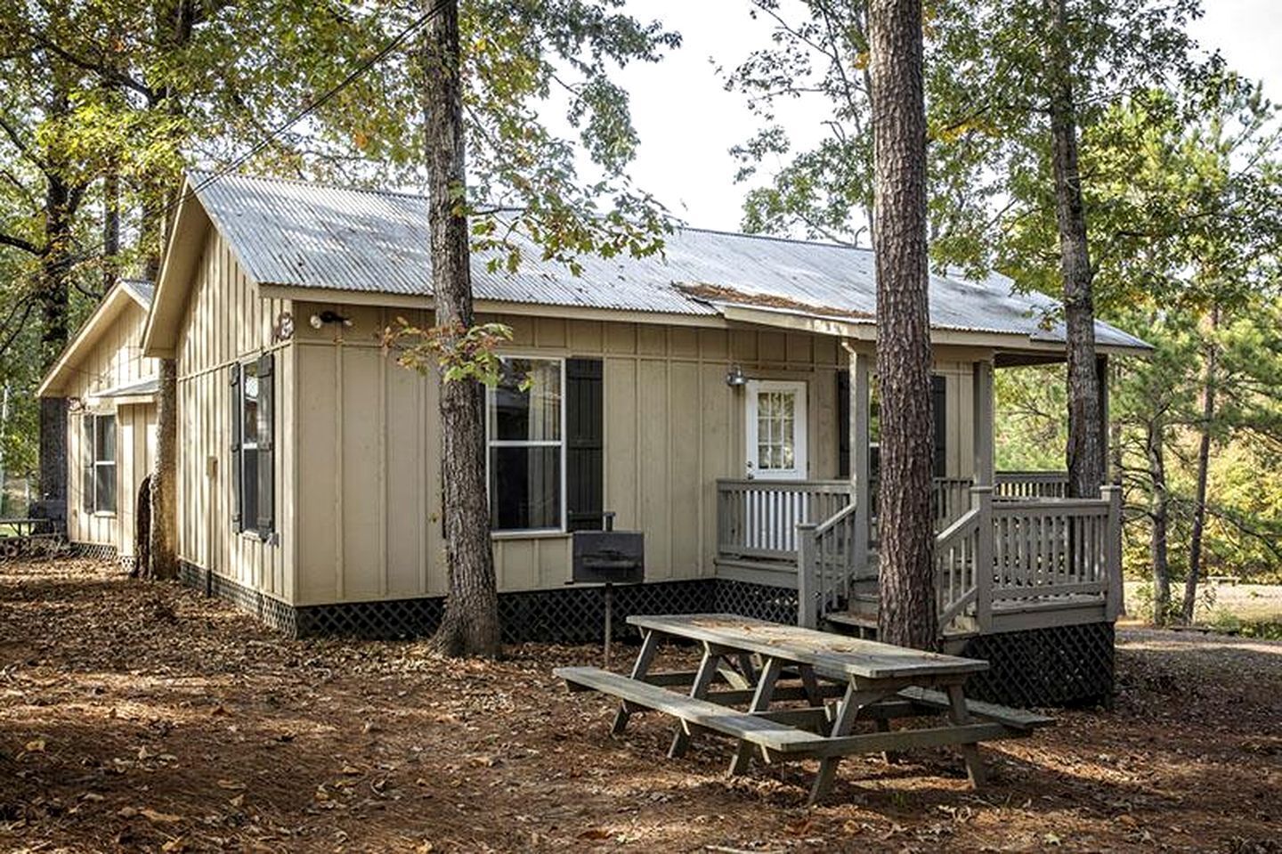 A cabin with a porch, a picnic table, and a small deck.