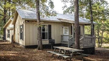 A cabin with a porch, a picnic table, and a small deck.