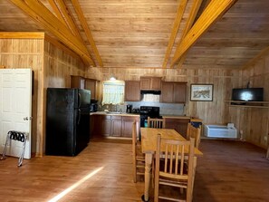 Un intérieur en bois comprenant une cuisine, un coin repas et une porte blanche.