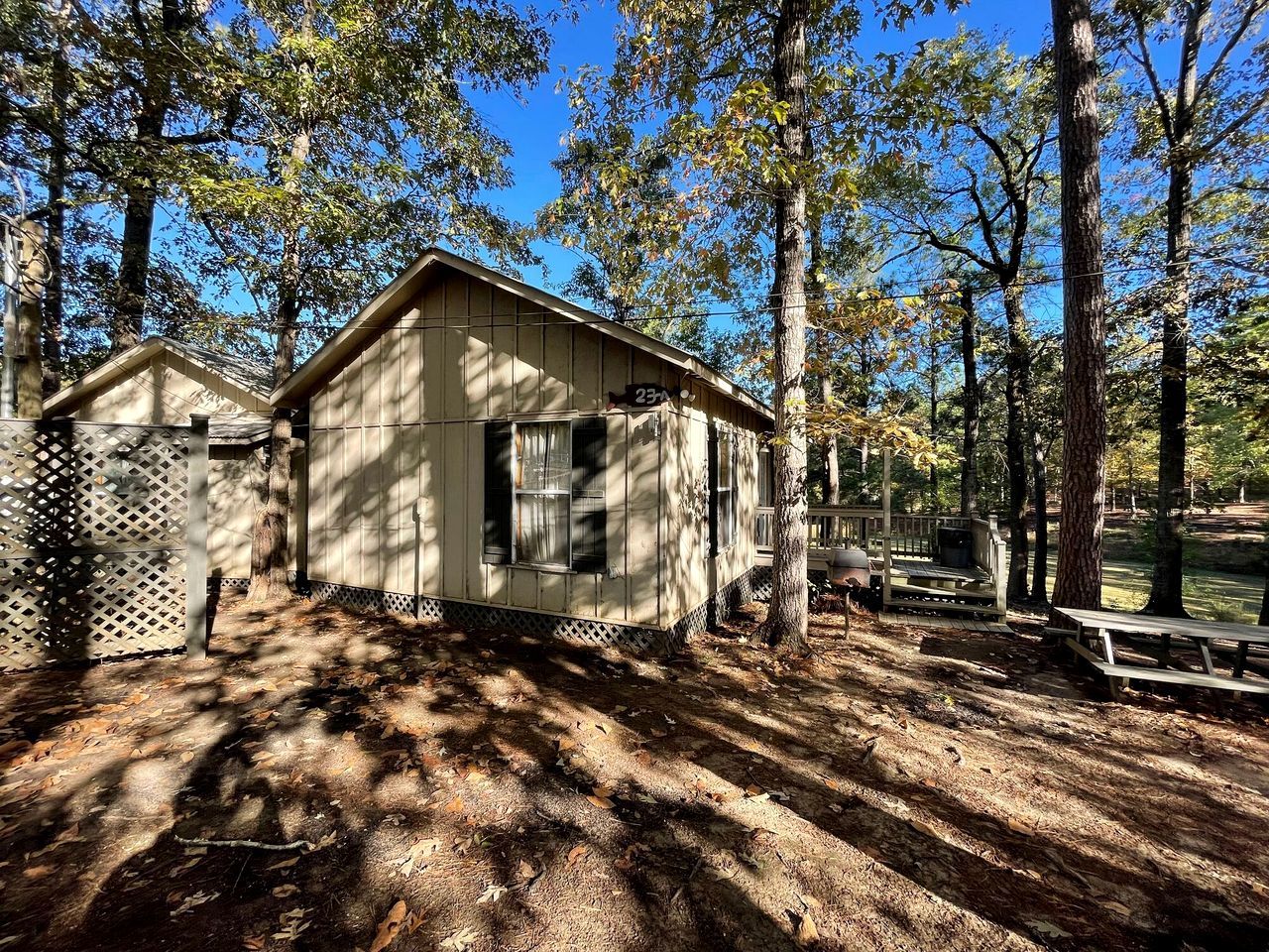 A cabin with a wooden exterior, a fenced yard, and picnic tables.