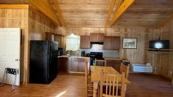 A wooden interior with a kitchen, dining area, and a white door.