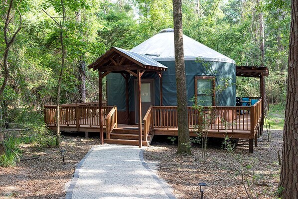 A cabin with a porch and a covered entrance, surrounded by trees.