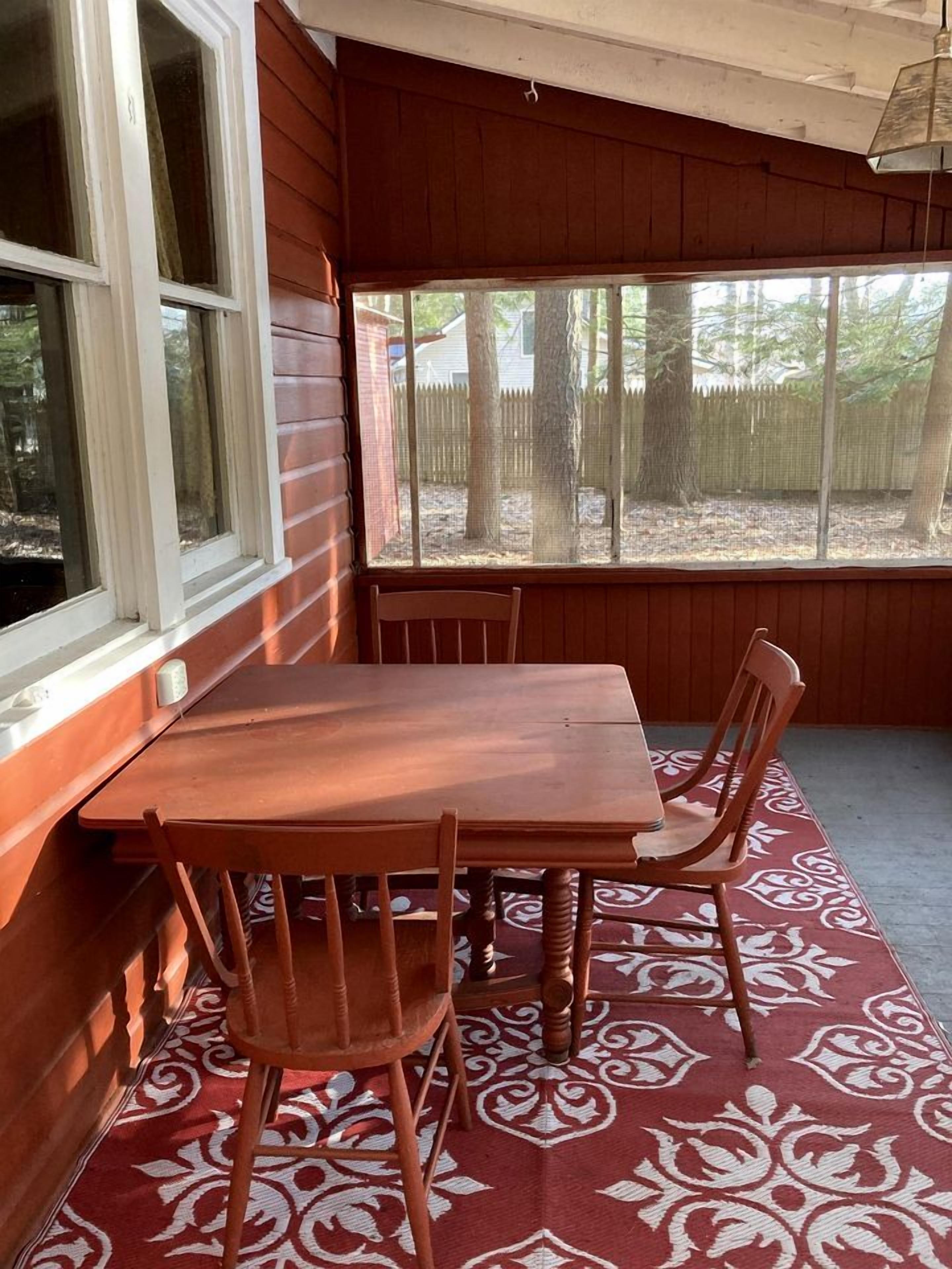 A wooden table with four chairs, a window, and a patterned rug.