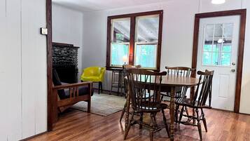 Un comedor con una mesa y sillas de madera, una silla amarilla y una chimenea.