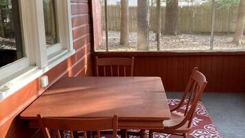 A wooden table with four chairs, a window, and a patterned rug.