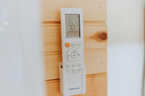 A white thermostat with a digital display, buttons for mode, set, OK, and other functions, and the brand name 'MRCOOL' on the bottom.