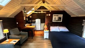 Una camera da letto mansardata accogliente con un letto, un divano, una scrivania e un angolo cottura.
