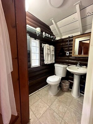 Ein kleines Badezimmer mit Toilette, Waschbecken und Fenster.