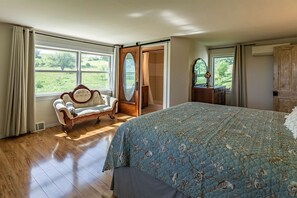 Un dormitorio con una cama grande, una silla antigua, un espejo y un armario.
