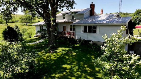 A two-story house with a front porch, surrounded by lush greenery and a well-maintained lawn.