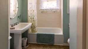 Une salle de bain avec un lavabo, un miroir et une baignoire.