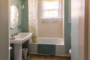 A bathroom with a sink, mirror, and bathtub.