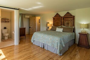 Ein Schlafzimmer mit einem hölzernen Bett, einem Nachttisch, einer Lampe, einem Kleiderschrank und einer Tür zu einem anderen Raum.