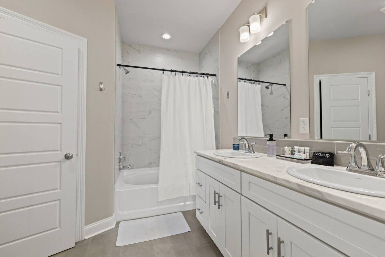 A bathroom with two sinks, a bathtub, a shower curtain, and a large mirror.