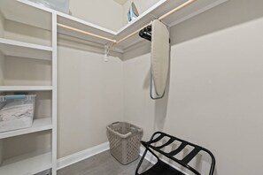 A storage closet with shelves, a hanging rack, and a laundry basket.