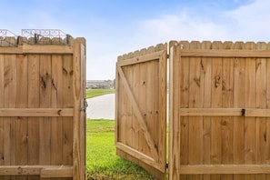 Due cancelli in legno aperti che danno su un vialetto lastricato.