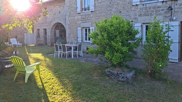 A stone building with a patio, outdoor seating, and a small tree.