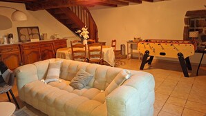Una sala de estar acogedora con sofá, vigas de madera, mesa de comedor y mesa de futbolín.