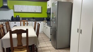 Una cocina con una mesa de comedor, sillas, un refrigerador y un lavavajillas.