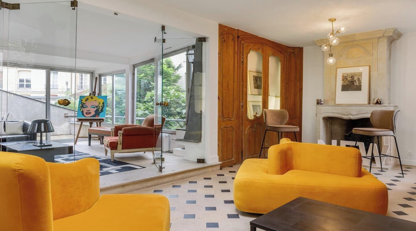 Un salon moderne avec une porte vitrée donnant sur un balcon, une cheminée et une grande fenêtre.