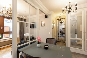 A dining area with a glass partition, a chandelier, and a clock on the wall. - Aapartments - Ideal City Center Location (Warszawa)