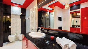 Ein modernes Badezimmer mit schwarzem Waschtisch, zwei Waschbecken, einem großen Spiegel und einer roten Akzentwand.