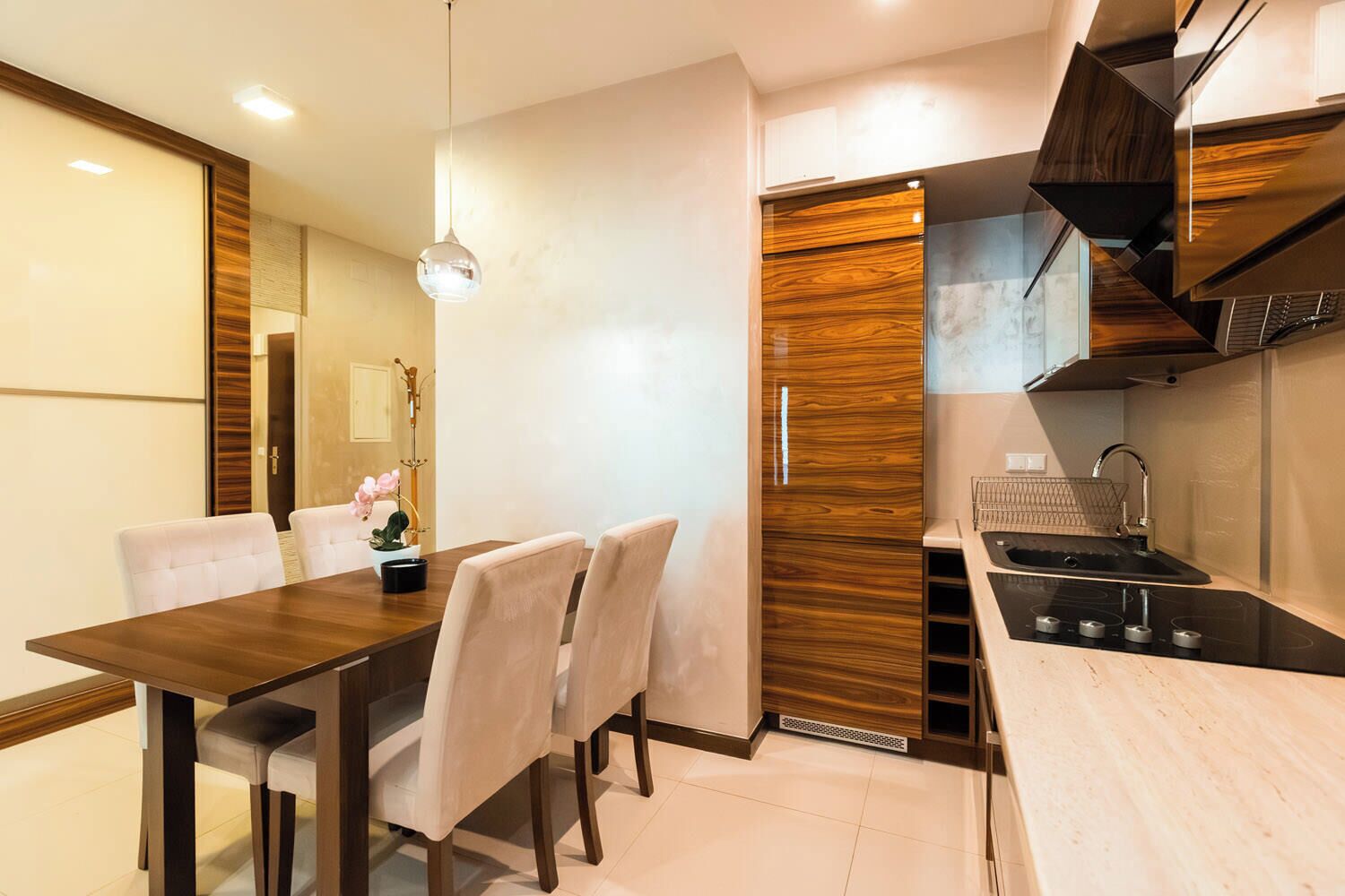 Una cocina moderna con comedor, que incluye un armario de madera, una estufa integrada y una lámpara colgante.