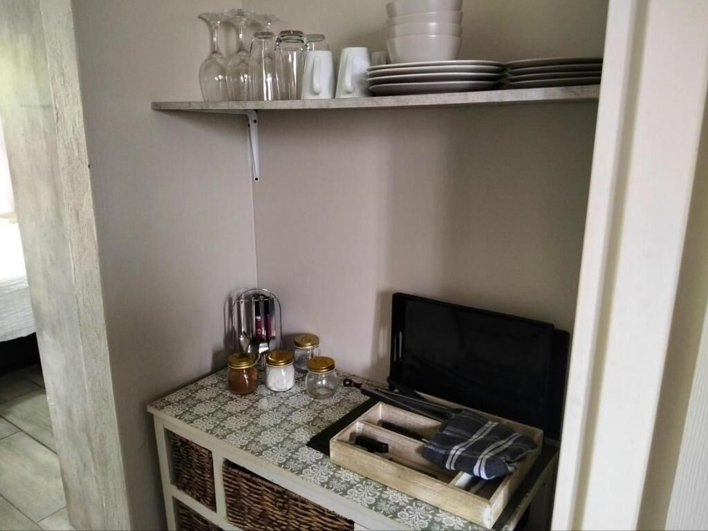 Uma área de cozinha com uma prateleira contendo copos, potes e pratos.