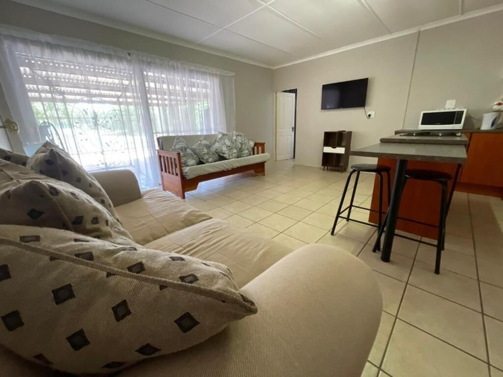 Quarto com cama, escrivaninha, televisão e janela com cortinas.
