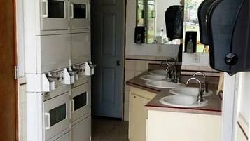 A compact kitchen with a microwave, stove, sink, and a trash bin.