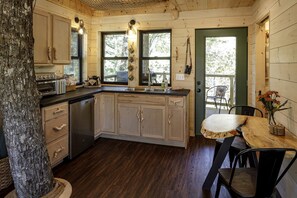 Une cuisine rustique dans un chalet, avec des meubles en bois, un four encastré et une table à manger avec des chaises.